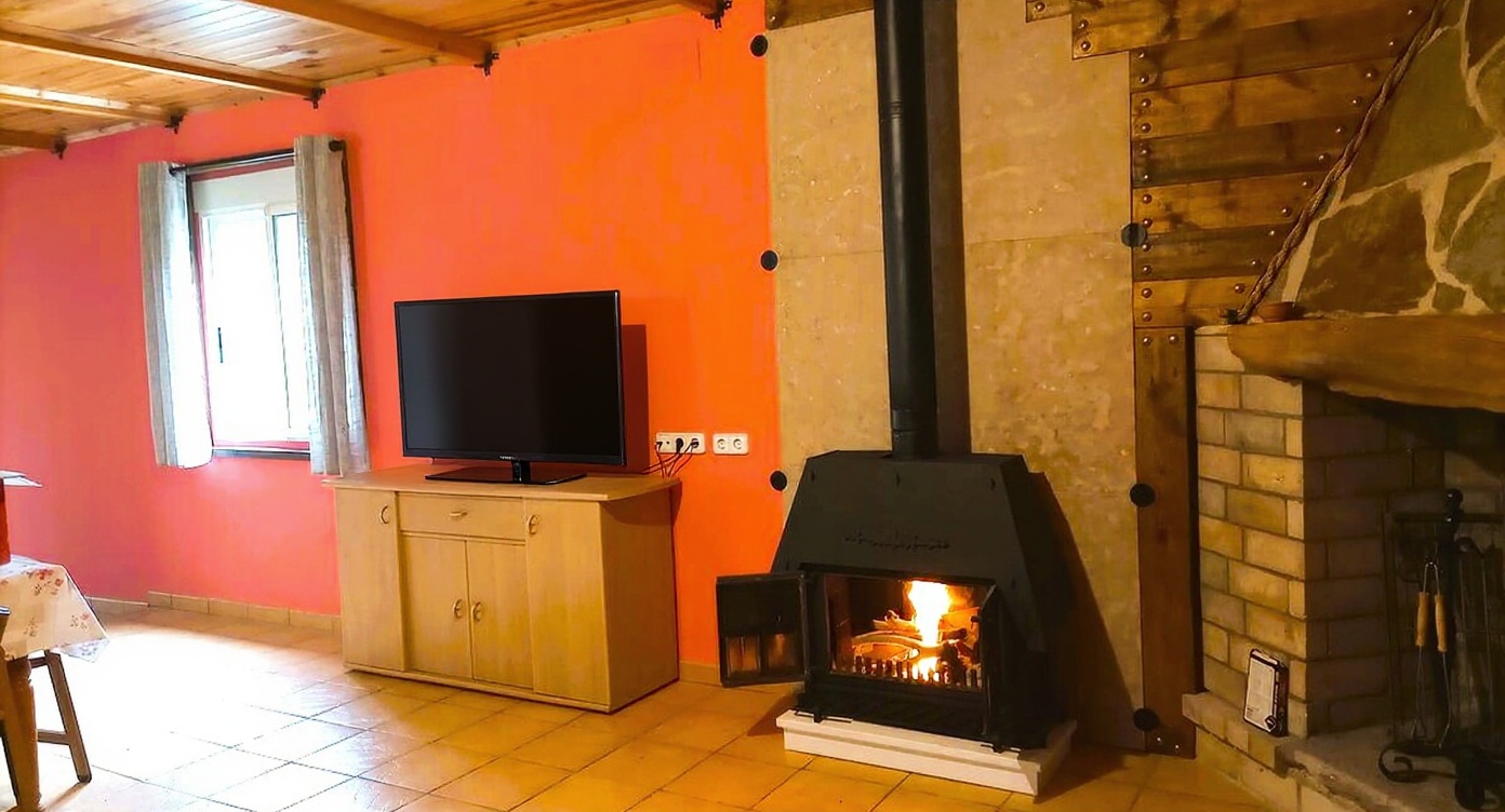 Estancia con estufa de leña encendida y TV